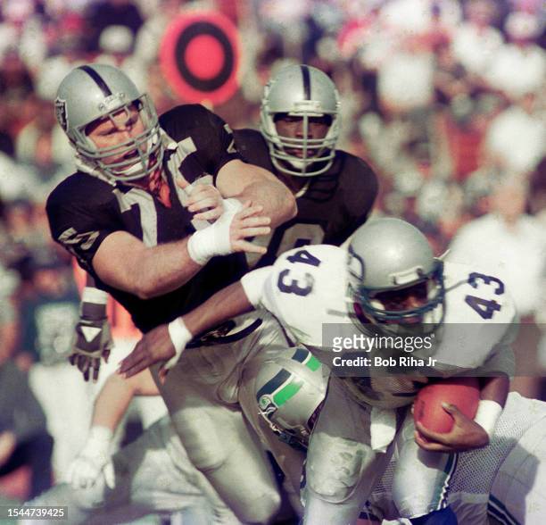 Seattle Seahawks Running Back Randall Morris eludes the grasp of Los Angeles Raiders Howie Long during game action against Seattle Seahawks, December...