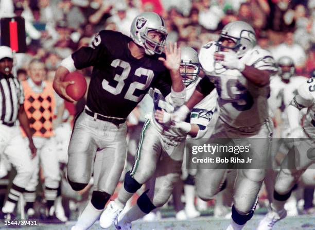 Los Angeles Raiders Running Back Marcus Allen runs to elude defenders during game action against Seattle Seahawks, December 15, 1985 in Los Angeles,...