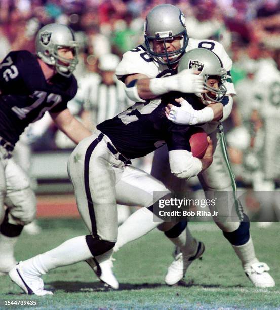 Los Angeles Raiders Running Back Marcus Allen runs to elude defenders during game action against Seattle Seahawks, December 15, 1985 in Los Angeles,...