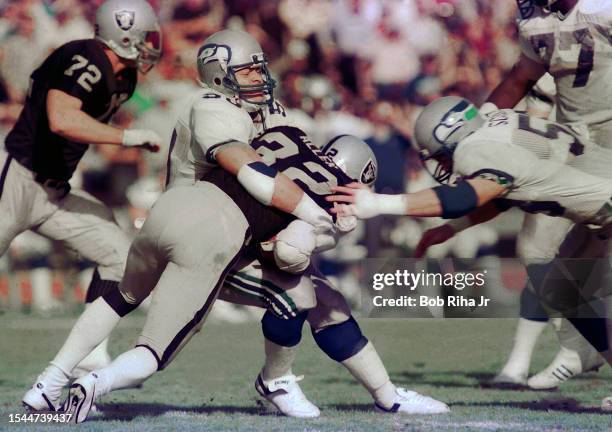 Los Angeles Raiders Running Back Marcus Allen runs to elude defenders during game action against Seattle Seahawks, December 15, 1985 in Los Angeles,...