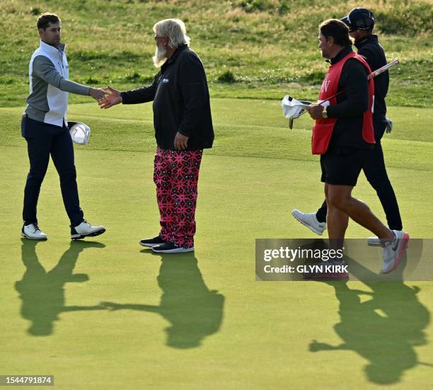 Golfer Taylor Moore shakes hands with US golfer John Daly after their round, on the 18th green, on day one of the 151st British Open Golf...