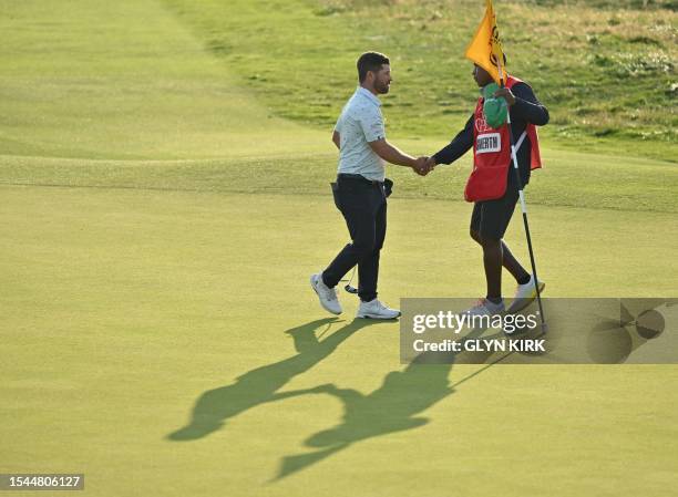 Sweden's David Lingmerth shakes hands with his caddie after holing his putt on the 18th green on day one of the 151st British Open Golf Championship...
