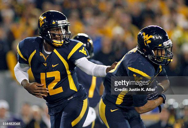 Geno Smith of the West Virginia Mountaineers hands the ball off against the Kansas State Wildcats during the game on October 20, 2012 at Mountaineer...