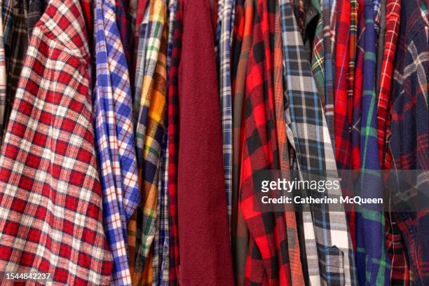 rack of vintage flannel shirts at antique flea market - flannel shirt stock pictures, royalty-free photos & images
