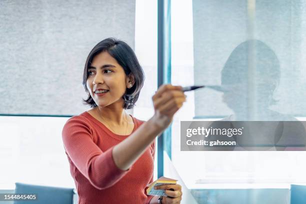 young businesswoman writing on white board in office - woman presenting stock pictures, royalty-free photos & images