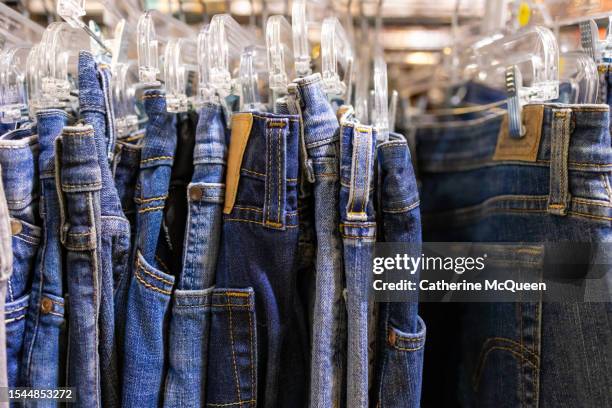 rack of vintage denim blue jeans at antique flea market - denim bildbanksfoton och bilder