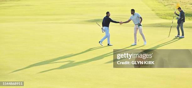 Golfer Justin Thomas shakes hands with US golfer Tony Finau on the 18th green on day one of the 151st British Open Golf Championship at Royal...