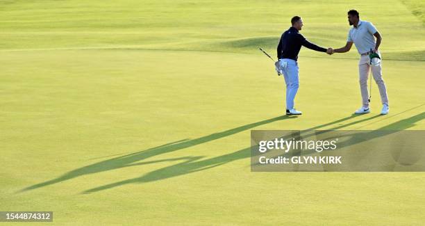 Golfer Justin Thomas shakes hands with US golfer Tony Finau on the 18th green on day one of the 151st British Open Golf Championship at Royal...
