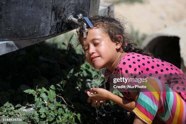 Palestinian girl rinses her head with water from a cistern next to her house during a heat wave and lengthy power cuts in Nahr al-Bared camp in Khan...