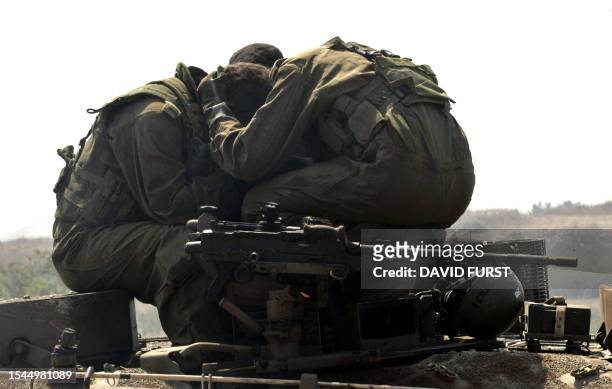 Israeli soldiers comfort each other after crossing the border back into Israel after an incursion inside southern Lebanon, 24 July 2006. Nine...