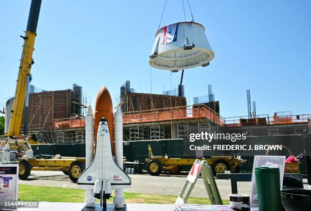 Model of the space shuttle Endeavour is seen on a table as the second of two aft skirts, the base of the solid rocket boosters for the retired space...