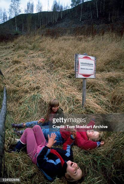 Children from the village of Crossen, East Germany, play on a uranium waste tip produced by a mine near the village, 1st March 1991. The sign behind...