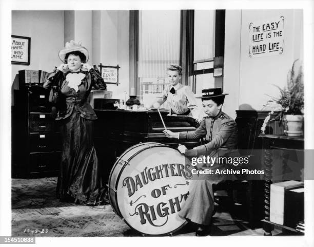 Marjorie Main plugs her ears while Vera-Ellen sits at a desk and Alice Pearce plays a giant drum in a scene from the film 'The Belle Of New York',...