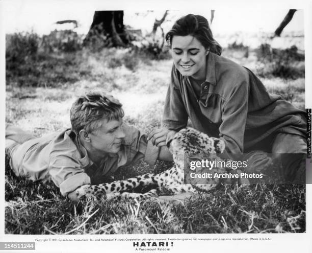 Hardy Krüger and Elsa Martinelli in the grass with wild cat on location in East Africa for the film 'Hatari!', 1962.