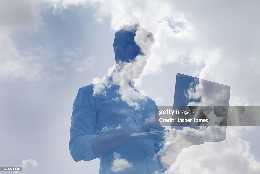 Double exposure of man using laptop and sky