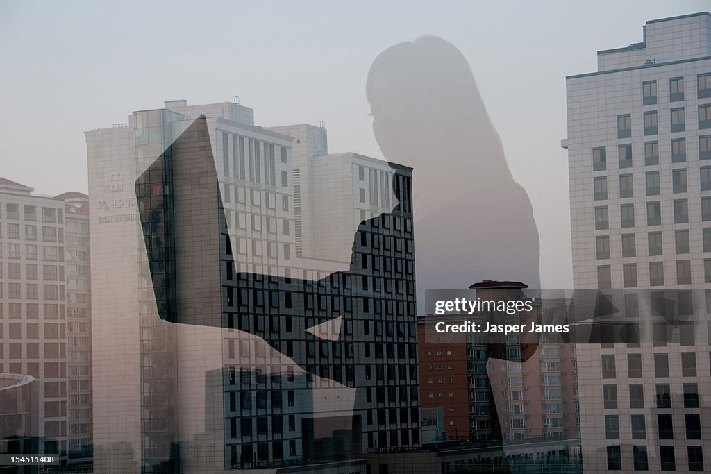 Double exposure of woman using laptop and city