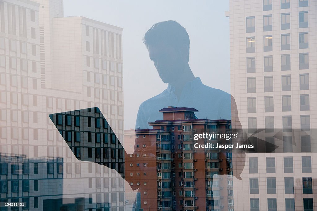 Double exposure of man using laptop and cityscape