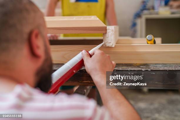 application de colle sur bois à l’atelier de menuiserie - collant description physique photos et images de collection
