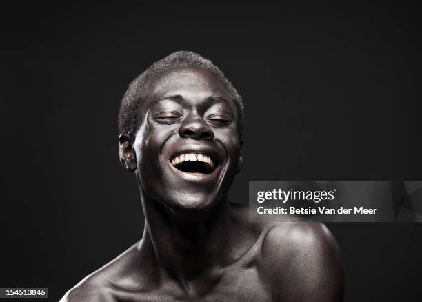 portrait of young black man laughing. - portrait on black background stock pictures, royalty-free photos & images