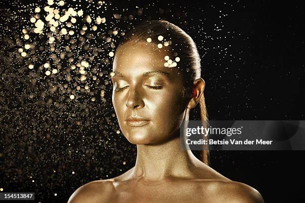 golden woman surrounded by sparkles. - female body painting stock-fotos und bilder