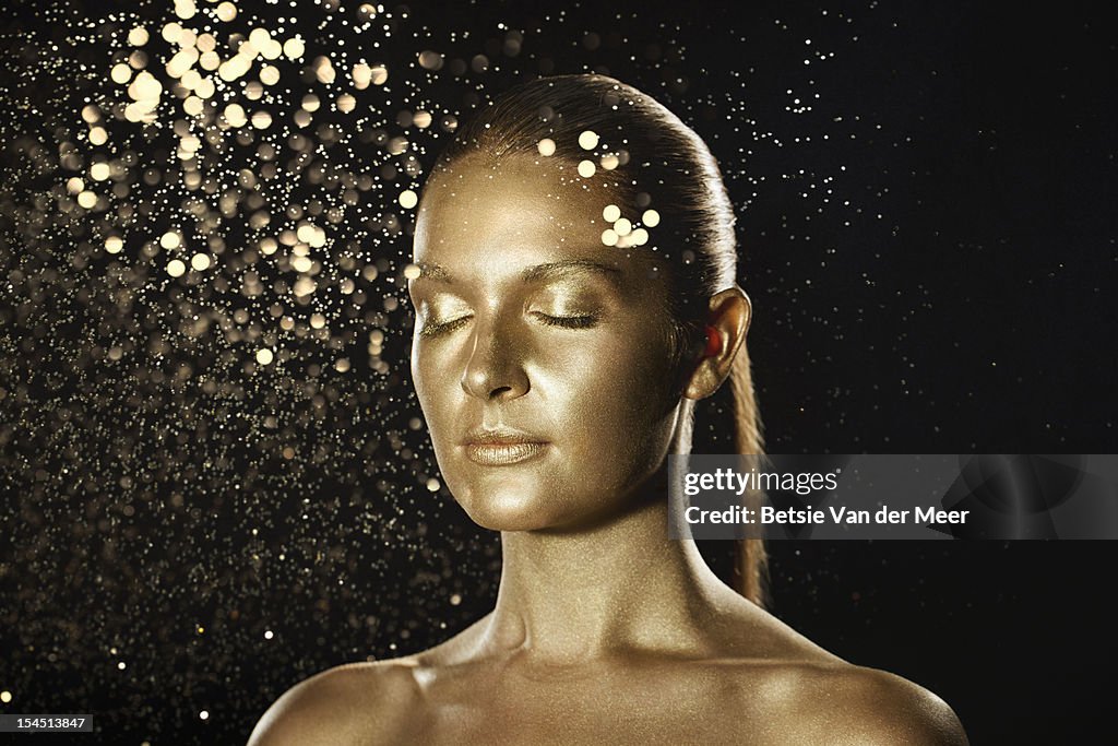 Golden woman surrounded by sparkles.