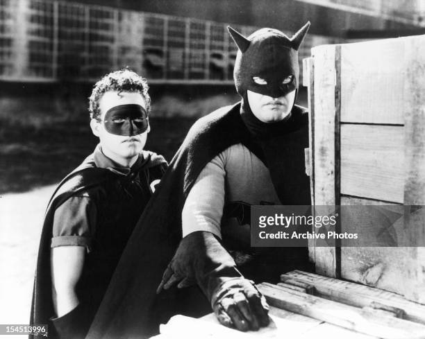 Douglas Croft and Lewis Wilson hide behind crates in a scene from the film 'Batman', 1943.