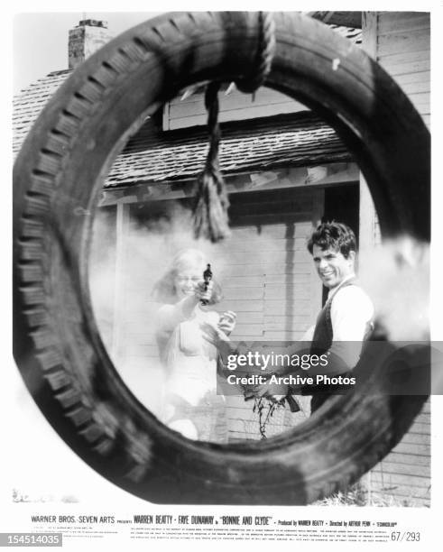 Faye Dunaway shoots through a tire as Warren Beatty watches in a scene from the film 'Bonnie And Clyde', 1967.