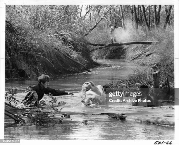 Michael J Pollard, Faye Dunaway, and Warren Beatty attempt to cross a creek in a scene from the film 'Bonnie And Clyde', 1967.