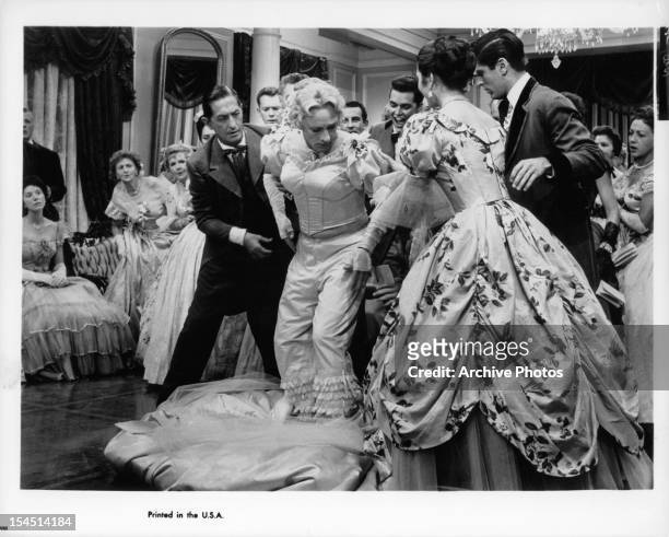 Bing Crosby in drag has his dressed pull out from under him before Richard Beymer and filled room in a scene from the film 'High Time', 1960.