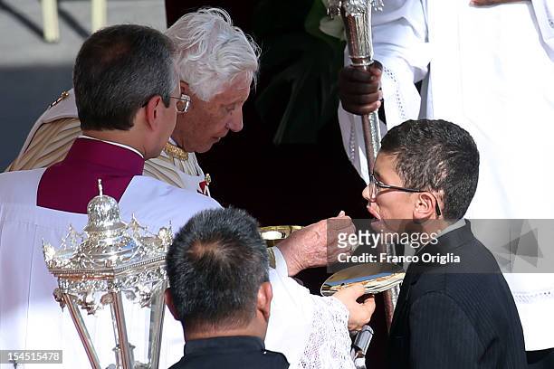Pope Benedict XVI gives communion to Jake Finkbonner , of Ferndale, Washington, during a canonization ceremony in St. Peter's Square on October 21,...