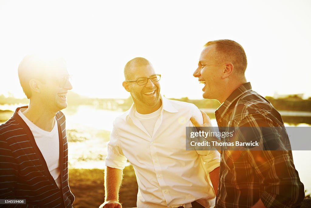 Gay couple in discussion with friend at sunset