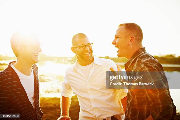 gay couple in discussion with friend at sunset - relaxed sunshine happy lens flare stock pictures, royalty-free photos & images