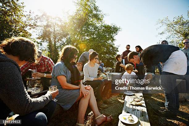 group of friends and family eating oysters outside - large group in park imagens e fotografias de stock