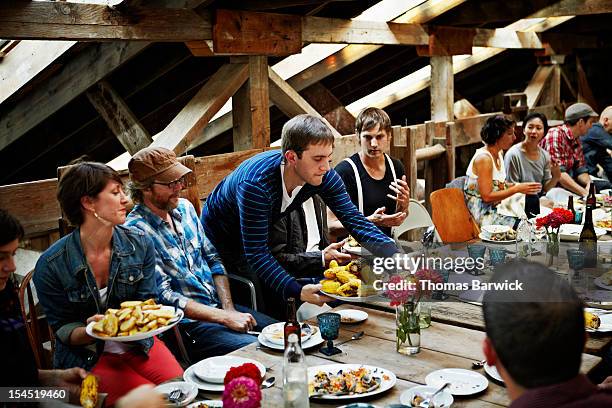man serving food to group of friends and family - eetkamer stockfoto's en -beelden