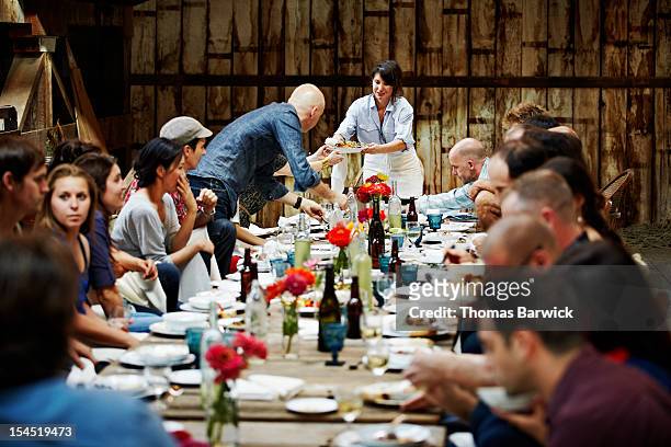 woman passing food to friends and family - festmahl stock-fotos und bilder