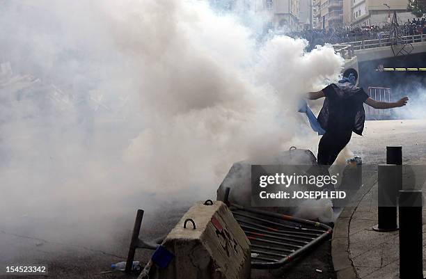 Lebanese supporter of the March 14 movement, which opposes the Syrian regime of President Bashar al-Assad, runs for cover from tear gas fired by...