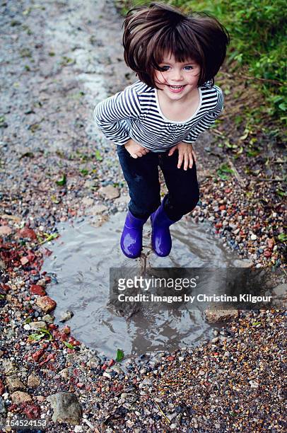 little girl jumping in a muddy puddle - 3 years brunette female alone caucasian stock pictures, royalty-free photos & images