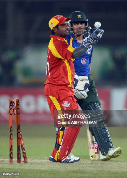 International World XI wicketkeeper Mohammad Shahzad celebrates after stumps to Pakistani cricketer Umer Akmal on October 21, 2012 during the second...