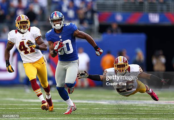 Victor Cruz of the New York Giants carries the ball past Madieu Williams and Josh Wilson of the Washington Redskins to score the game winning...