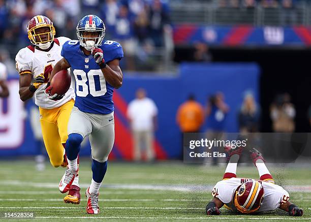 Victor Cruz of the New York Giants carries the ball past Madieu Williams and Josh Wilson of the Washington Redskins to score the game winning...