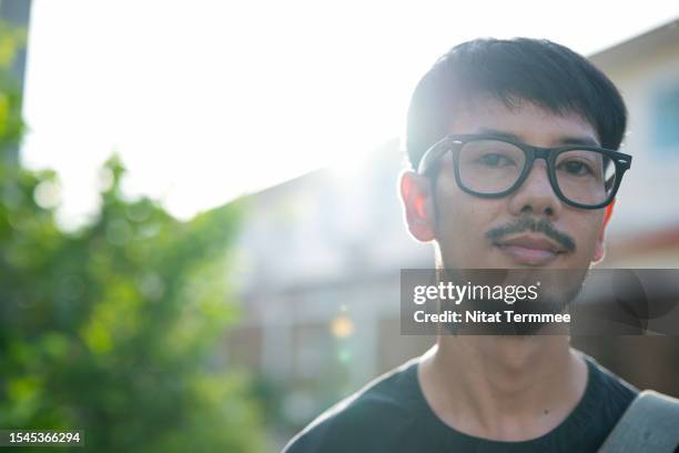 autonomy over your work of freelancing. a portrait of a stylish southeast asian man standing in a city street, looking concentrated and confident. - weichzeichner stock-fotos und bilder