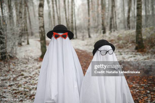 mystical ghostly gathering: kids in ghost costumes, donning glasses and hats, converge in the forest for a magical halloween adventure. - verkleden stockfoto's en -beelden