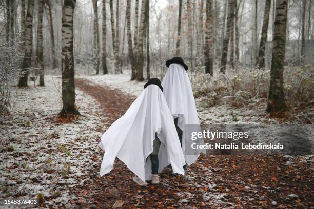 ghostly carousel in the snow: kids embrace the spooky spirit, wearing ghost costume hats, as they spin through the forest's first snow. creating mysterious halloween photos. - halloween poster stock pictures, royalty-free photos & images