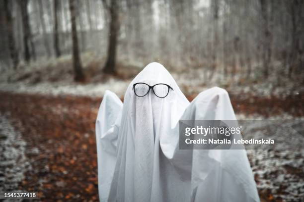 mesmerizing forest spirits: ghostly entities in glasses, adorned in children's ghost costumes, evoke a sense of mystery in the gloomy forest with first snow. embracing the essence of halloween in the wintry ambiance. - cute monster stock pictures, royalty-free photos & images