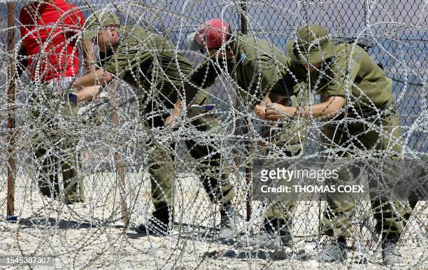 Israeli soldiers fix a new part of barbed wire fence at the Israeli-Lebanon border near the southern Lebanese town of Hula, 12 September 2006....