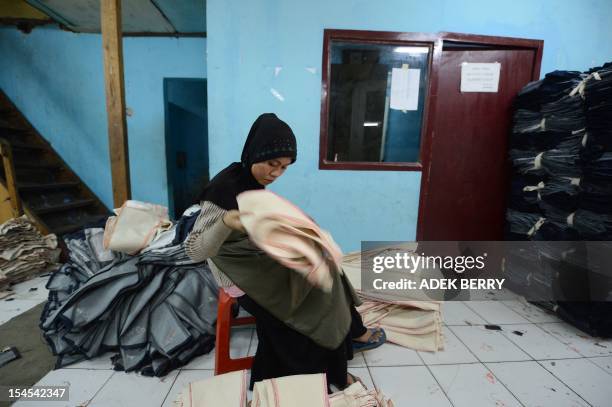 This picture taken on October 21, 2012 shows an Indonesian worker sorts clothes at a workshop in a small entreprise village in Jakarta. Indonesia's...