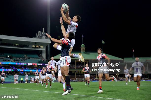 Xavier Coates of the Storm leaps into the air to beat Fetalaiga Pauga of the Roosters to score his hat track during the round 20 NRL match between...