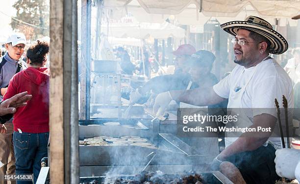 Milton Contreras, who owns El Boqueron II with his father, flips pupusas through a haze of smoke as he talks with customers at the World of...