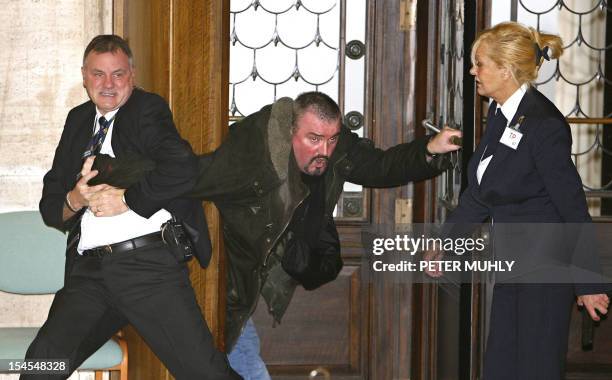 Security officials remove a handgun from the grip of former Northern Ireland Protestant paramilitant Michael Stone at Stormont Parliament buildings,...