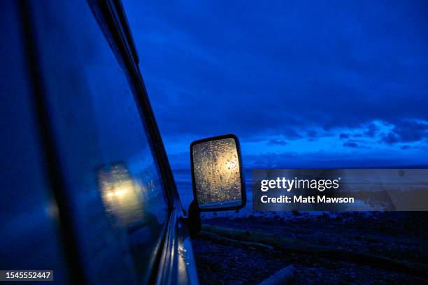 golden light reflecting on a rear-view mirror of a camper van on a rainy night night while camping on vancouver island bc canada - carmanah walbran provincial park stock pictures, royalty-free photos & images